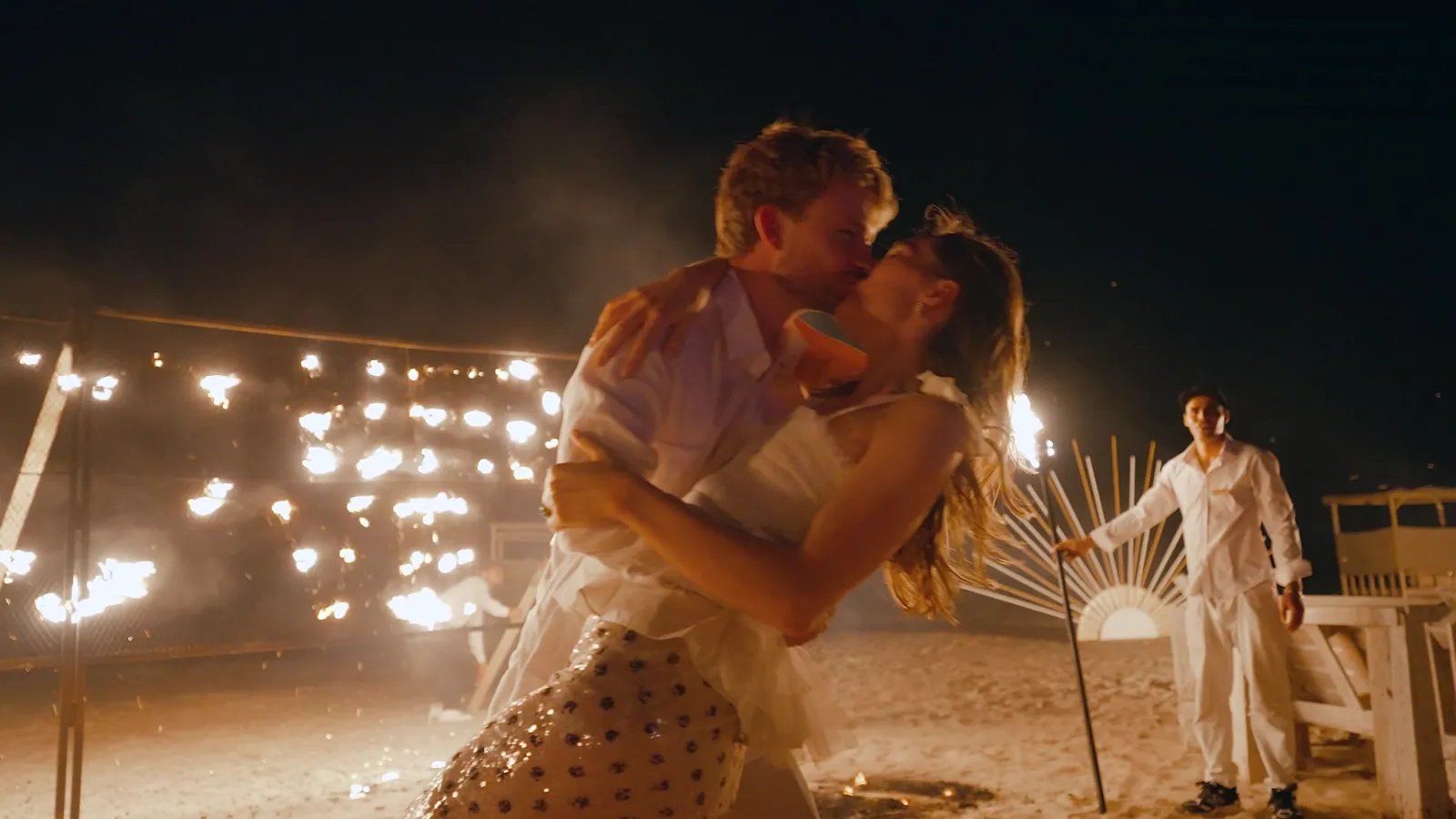 Bride and groom kissing during a fire show on the beach at night in Dakhla
